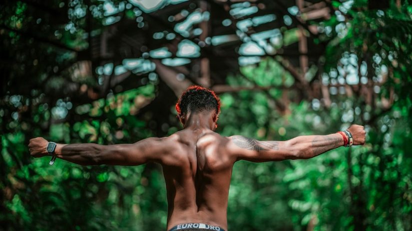 a man with his arms stretched out in the woods